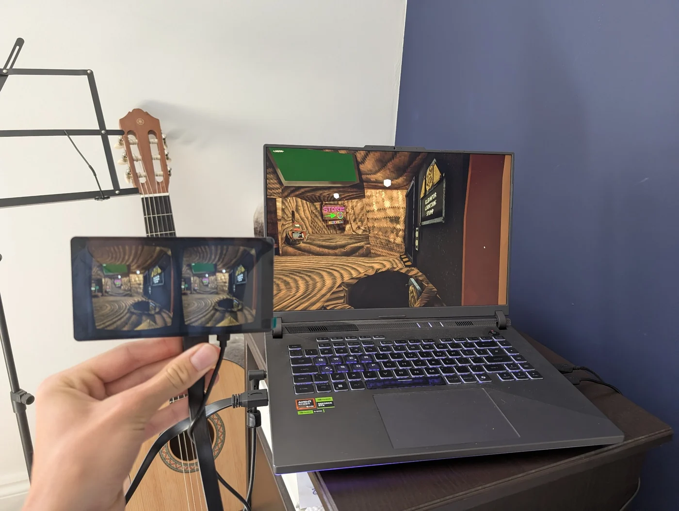 The headset's stereo display held up beside a gaming laptop, both showing the same 3D scene